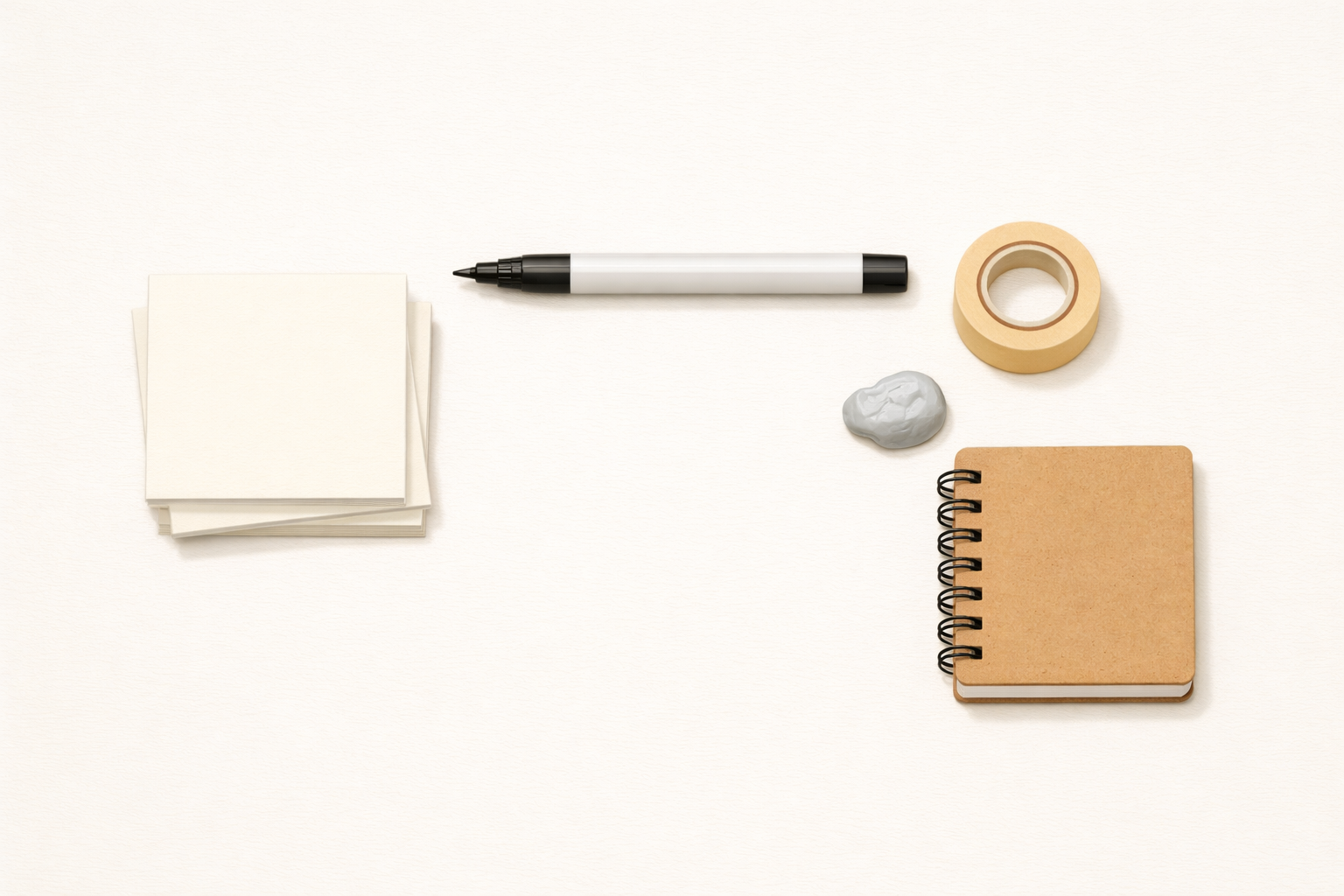 Sticky notes, a marker, removable tape, poster putty, and a small notebook laid out on a table.